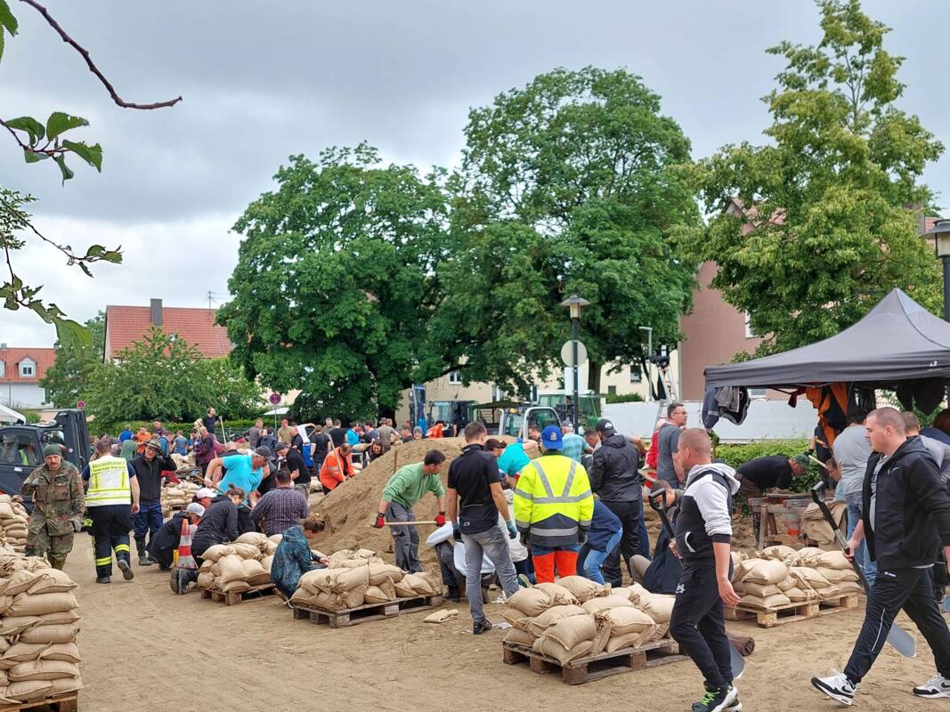 Helfer füllen am Feuerwehrhaus Manching beim Hochwasser 2024 Sandsäcke